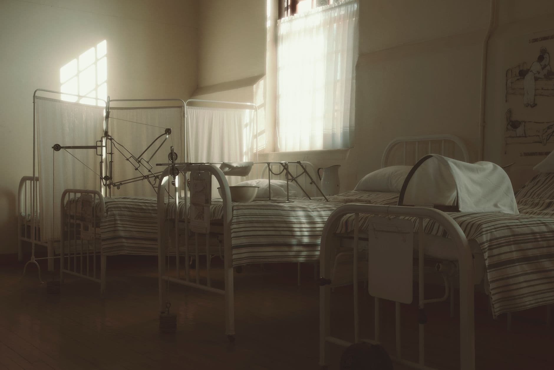 A dim, quiet vintage hospital room with empty beds