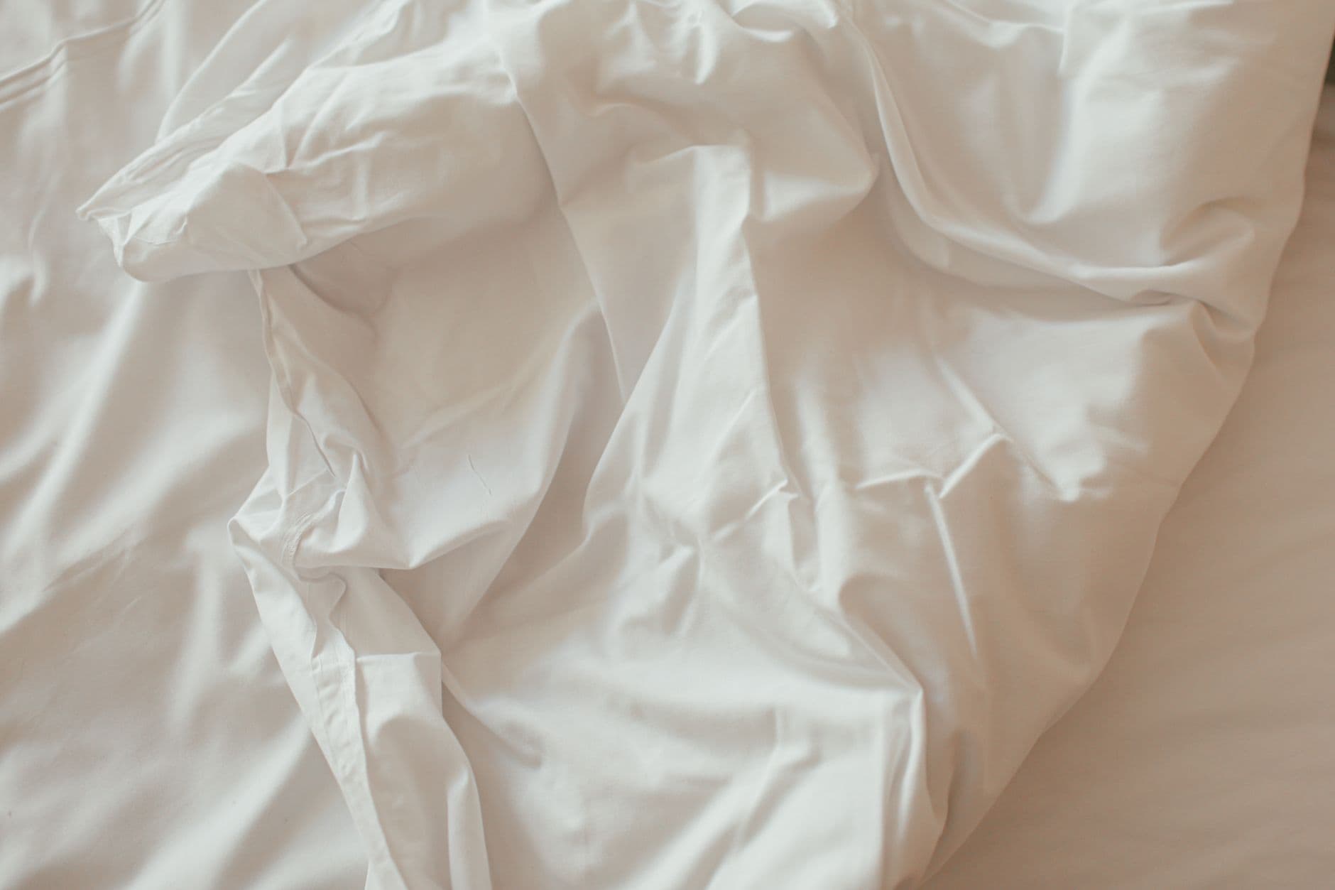 A close-up of crumpled white bedsheets in soft, natural light